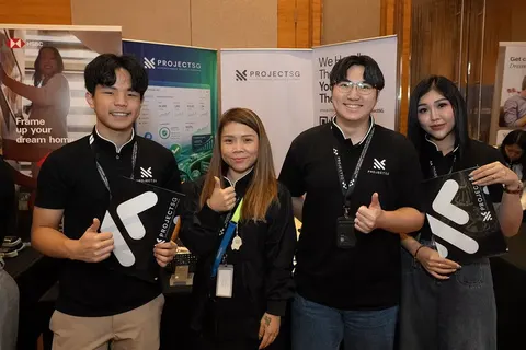 Four ProjectSG team members in black ProjectSG shirts holding branded fans at an exhibition booth