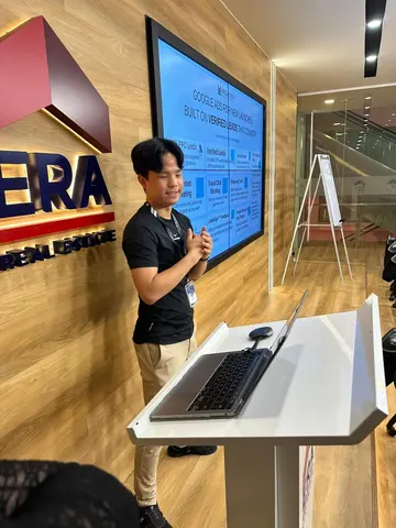 A ProjectSG presenter at a lectern in an ERA training room, with a slide on Google Ads for new launches on the screens behind